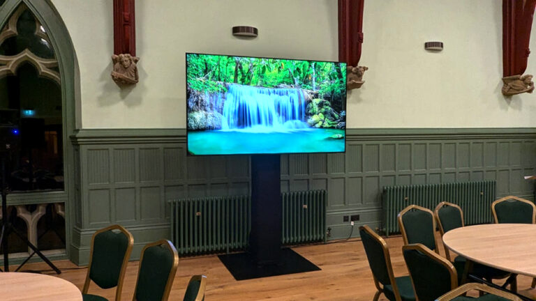 An 85" Samsung TV with black stand for conferences.